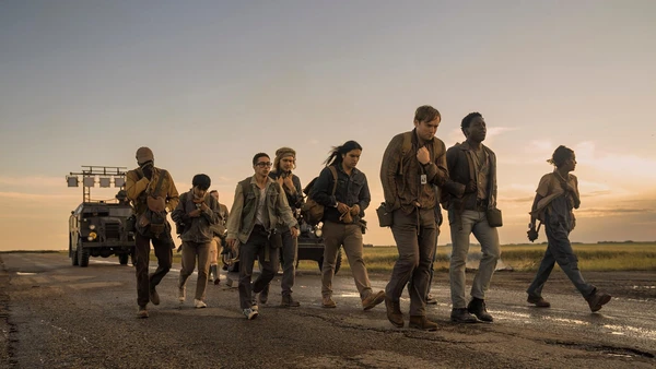 A group walks on a road at sunset in The Long Walk.