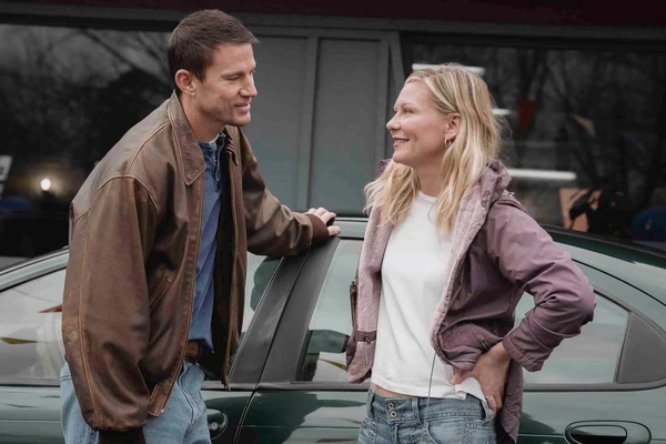 A man and a woman converse by a car in Roofman.